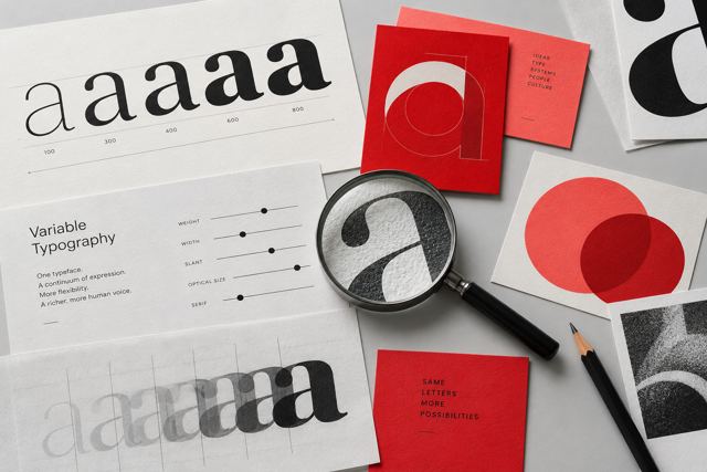 Typografiske prøver og røde identitetskort på et arbejdsbord.